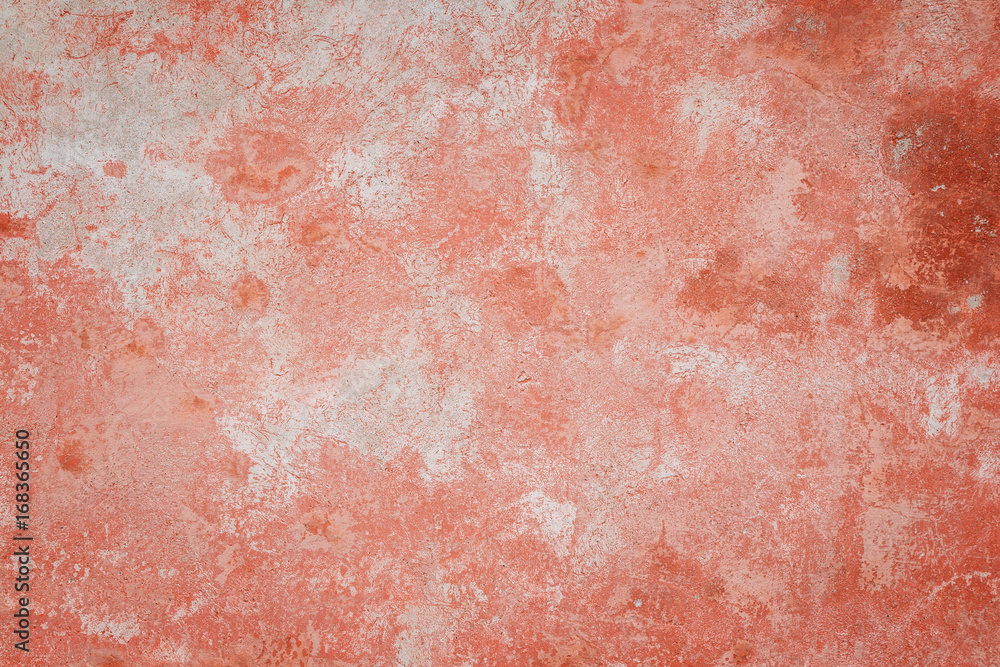 Fototapeta premium Close-up of a weathered and aged concrete wall, bleached red paint partly peeled off. Texture background with vignette.