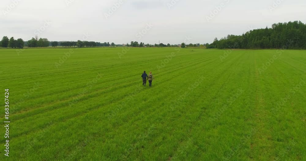 Young couple guy and girl running across the field in slow motion. Aerial footage. Young couple guy and girl running across the field in slow motion. Aerial footage.
