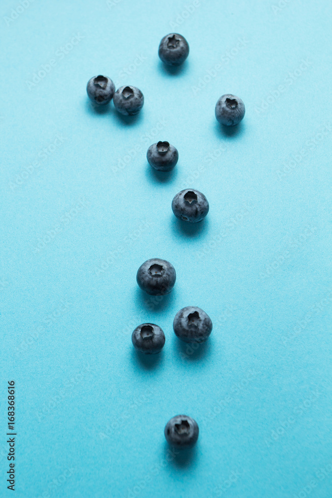 Ripe spilled blueberries on a blue background, vertically. Ripe spilled blueberries on a blue background, vertically.