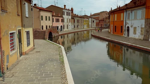 panning shot of channel in Comacchio, lagoon city with colorful houses and water flowing in canals in Italy, color graded clip photo