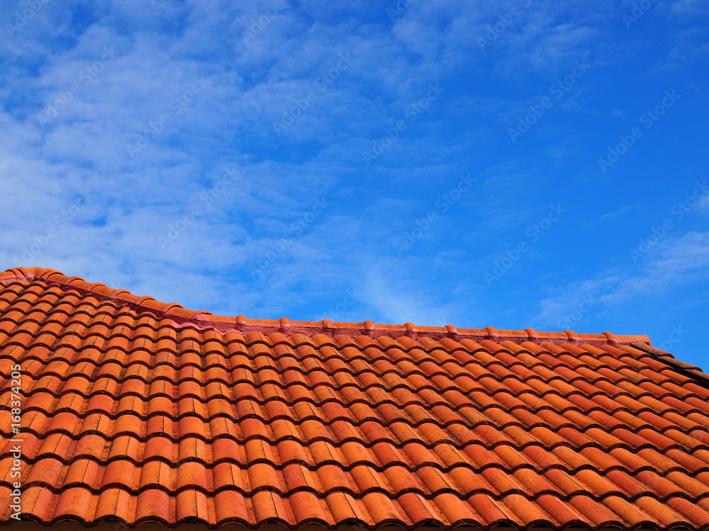 Orange cement tile ladder step like roof, with blue sky and fade distributed white cloud background Orange cement tile ladder step like roof, with blue sky and fade distributed white cloud background