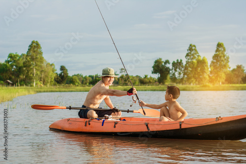 Son and father catch fish from a boat at sunset,a happy time for the holidays. photo