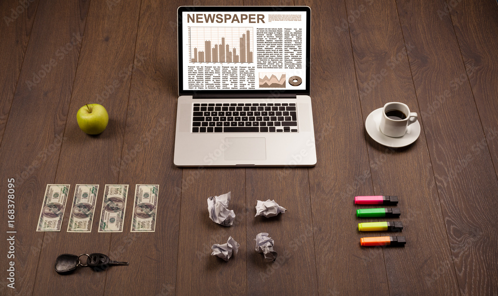 Business laptop with stock market report on wooden desk Business laptop with stock market report on wooden desk