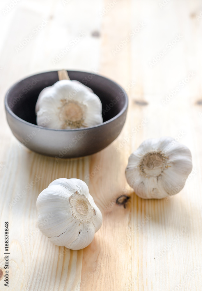 Garlic in black bowl on wooden table background Garlic in black bowl on wooden table background