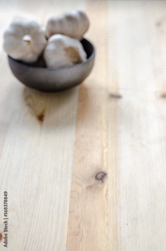 Garlic in black bowl on wooden table background Garlic in black bowl on wooden table background