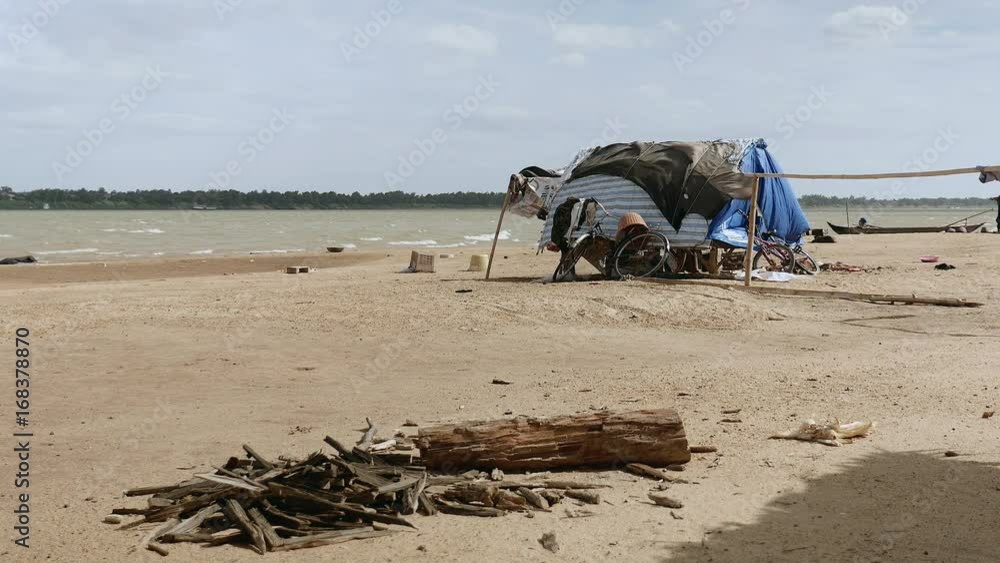 Small fishing house on the riverside on a windy day. Old firewood in the foreground Small fishing house on the riverside on a windy day. Old firewood in the foreground