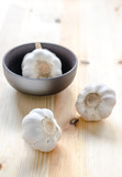Garlic in black bowl on wooden table background