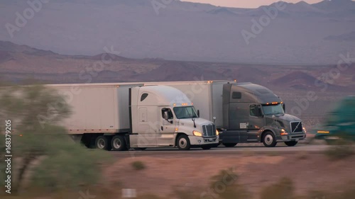 4K CLOSE UP: Freight semi truck driving and transporting cargo container on busy highway, delivering goods. Trucks speeding and overtaking photo