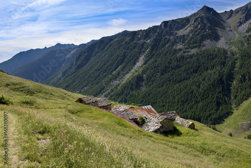 Roof of old house with view on mountains. Alpine landscape along the high road, North Italy