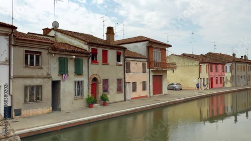 cinematic view of picturesque street of lagoon town with colorful houses and water flowing in canals in Italy, color graded clip photo