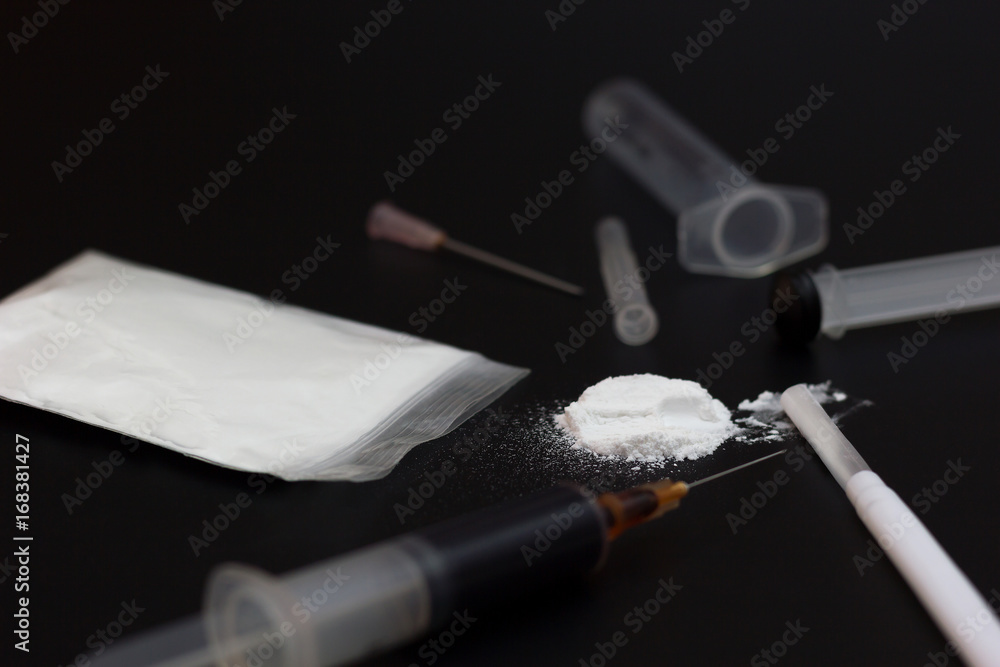 Naklejka premium Fake Heroin or diacetylmorphine bag and syringes placed side by side. Low key addictive substance on darkness background.