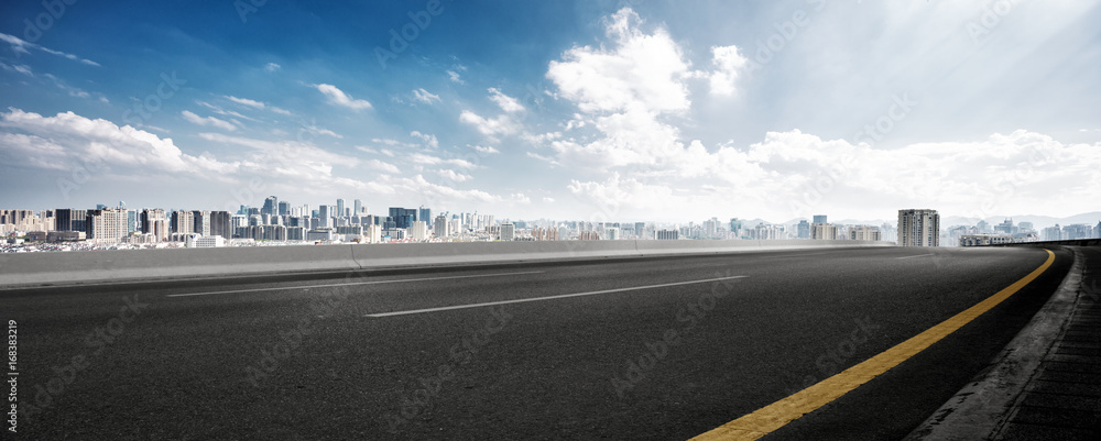 empty road and cityscape of modern city against cloud sky - obrazy, fototapety, plakaty 