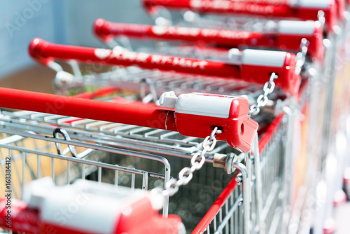 Row of shopping carts with red handles on evening blurry background near entrance of supermarket in winter