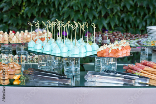Appetizers, finger food, party food, sliders. Canape, tapas. Served table at summer terrace cafe. Catering service. Outdoor restaurant table with food.