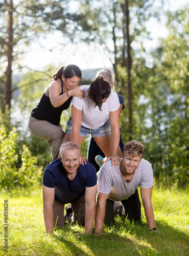Happy Coworkers Making Human Pyramid On Grassy Field