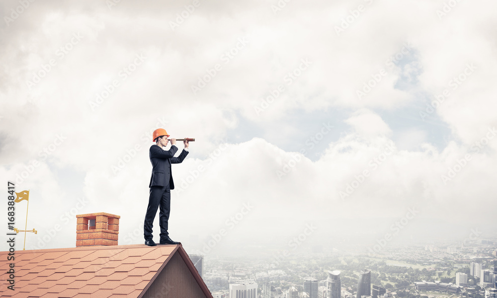 Engineer man standing on roof and looking in spyglass. Mixed med Engineer man standing on roof and looking in spyglass. Mixed med
