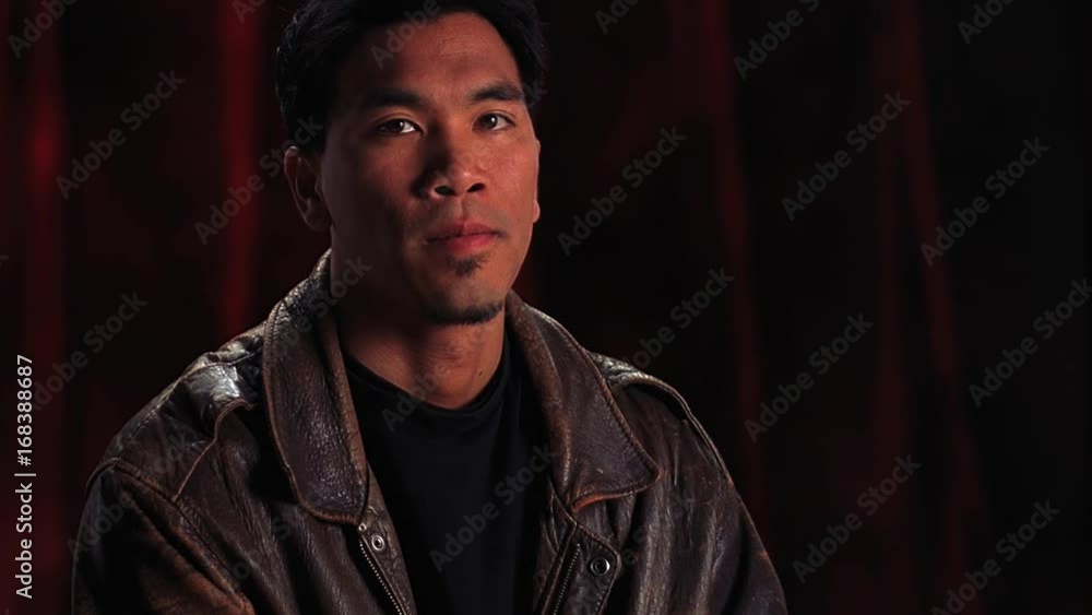 Portrait of serious young Asian man in leather bomber jacket. Portrait of serious young Asian man in leather bomber jacket.