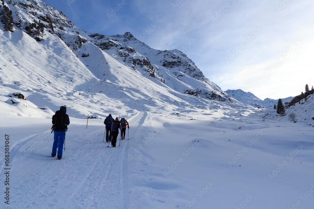 Group of people hiking on wintery snowy path and mountain panorama in Stubai Alps, Austria