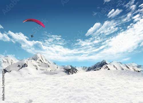 Mountain landscape with snow and man flying in the sky