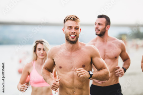 Group of young attractive people fitness workout. They having fun and running at beach.