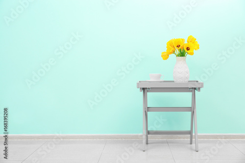 Wallpaper Mural Creative table with beautiful bouquet of flowers and cup near color wall Torontodigital.ca