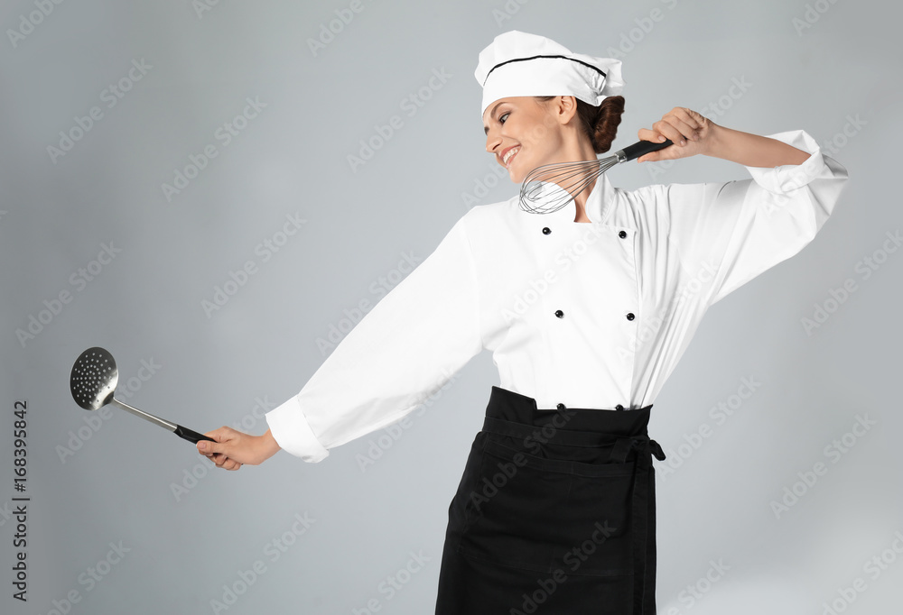 Naklejka premium Young female chef with utensils on light background