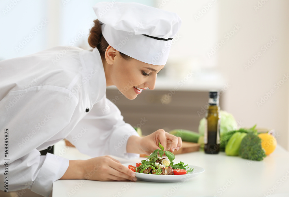 Young female chef cooking in kitchen Young female chef cooking in kitchen