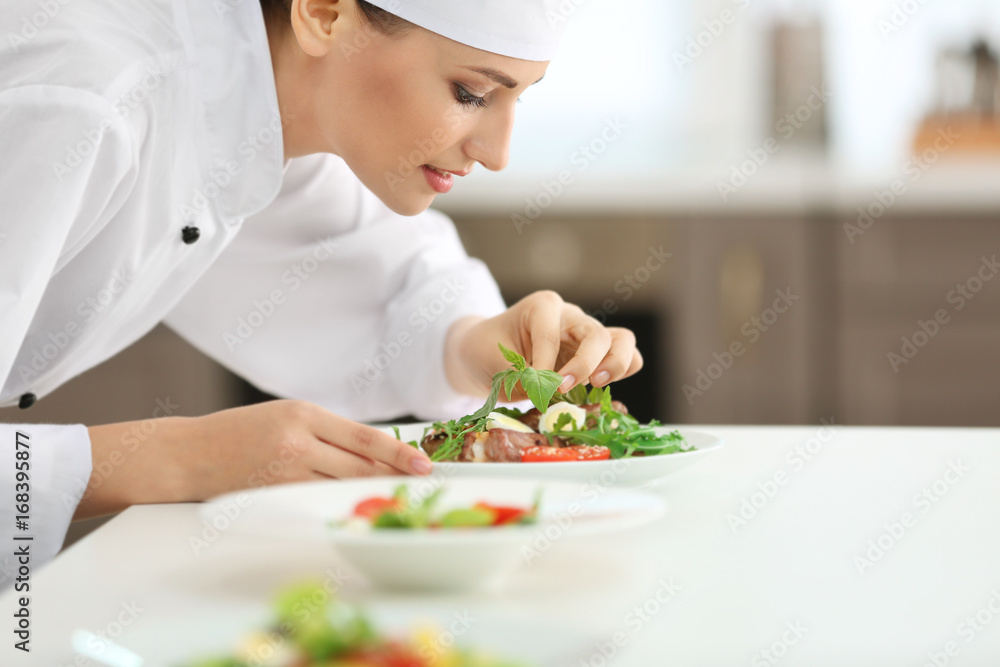 Young female chef cooking in kitchen Young female chef cooking in kitchen