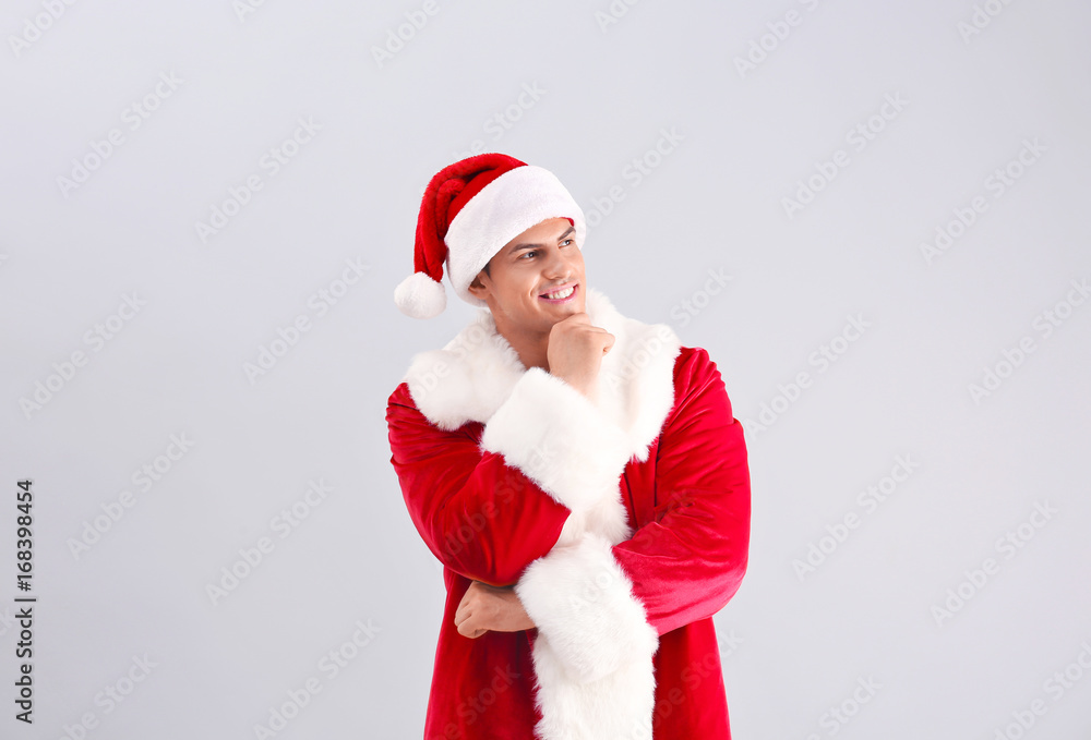 Handsome man in Santa Claus costume on light background Handsome man in Santa Claus costume on light background