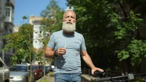 Male vaper with bicycle dreaming while walking