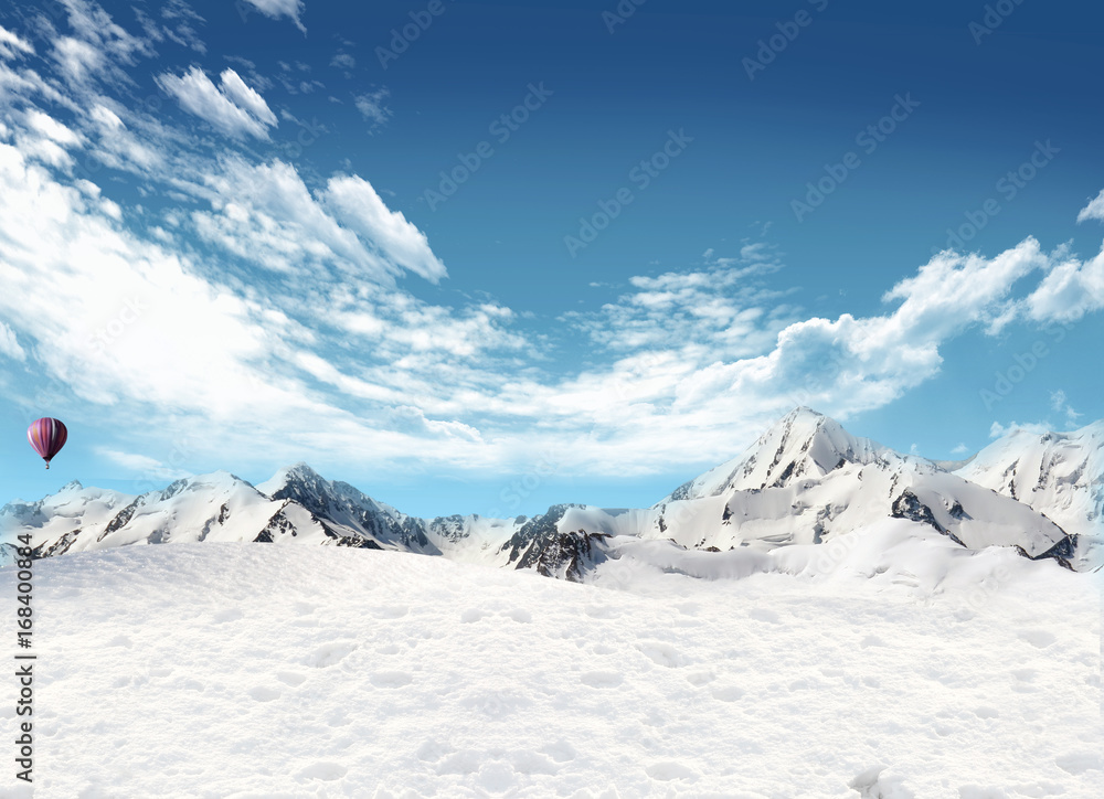 Mountain landscape with snow and hot air balloon flying in the sky