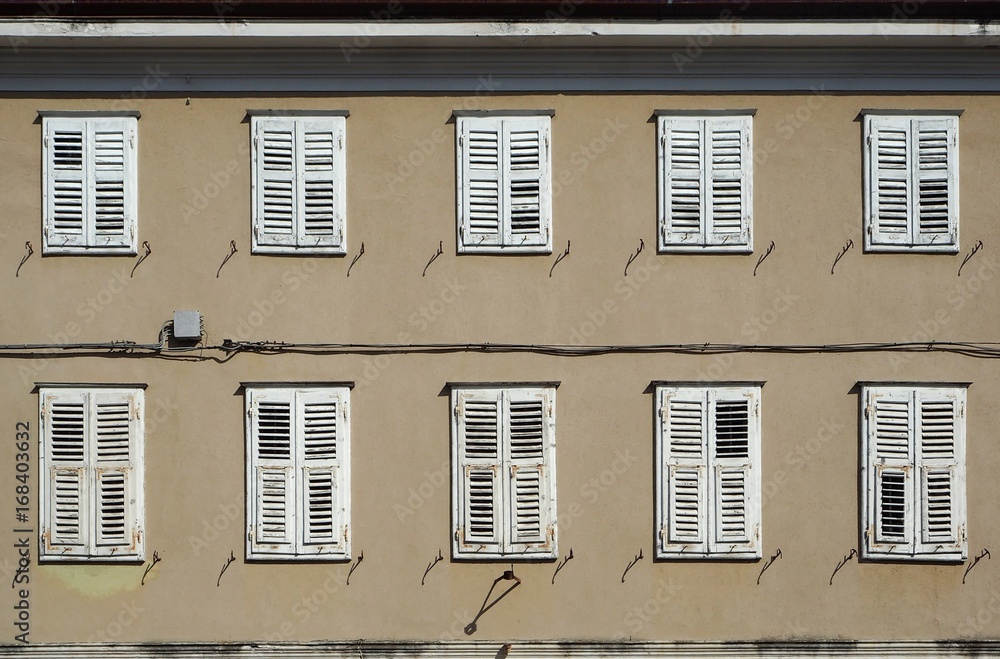 Traditional european  wooden shutters on a   brown facade of an old  residential building
