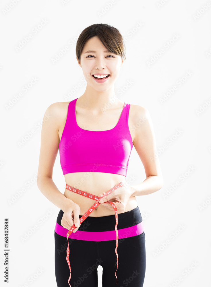 Fit young woman taking measurements of her body.