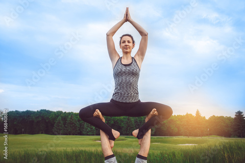 Fototapeta Naklejka Na Ścianę i Meble -  People practice acro yoga outdoors healthy lifestyle