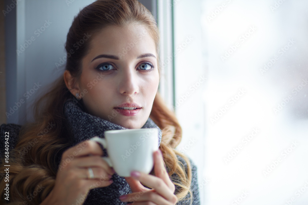 Young pretty woman in wool sweater with white coffee cup in hands Young pretty woman in wool sweater with white coffee cup in hands