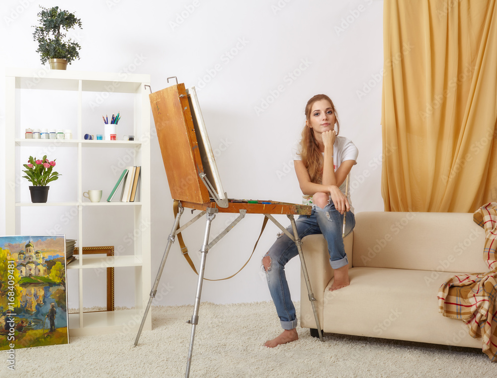 Painter female with wooden sketchbook sitting on sofa and painting Painter female with wooden sketchbook sitting on sofa and painting