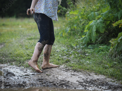 Child's feet covered with dirt. Green grass, dirt