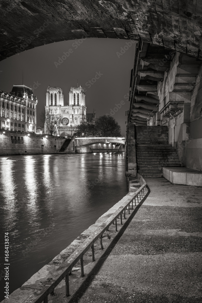 Naklejka premium Katedra Notre Dame de Paris z brzegów Sekwany w nocy w czerni i bieli. Ile de la Cite, Paryż, Francja