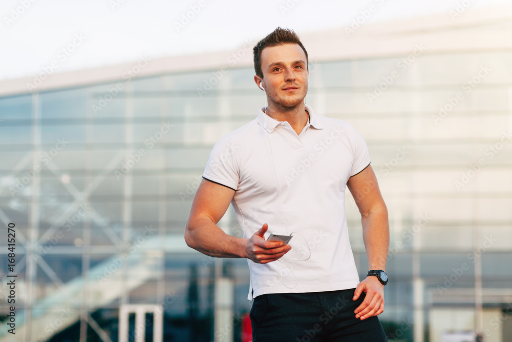 Handsome young man in white T-shirt using smartphone on Airport Parking