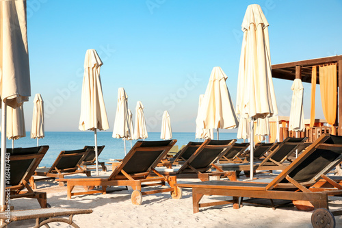Empty sunbeds with patio umbrellas on beach © Africa Studio