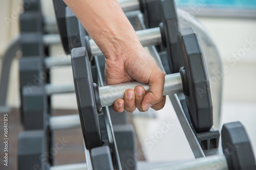 hand of sport man is holding dumbbell, exercising working out at the gym or fitness.