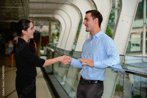 businessman and businesswoman shaking hands for success agreement and talk about business, outdoor