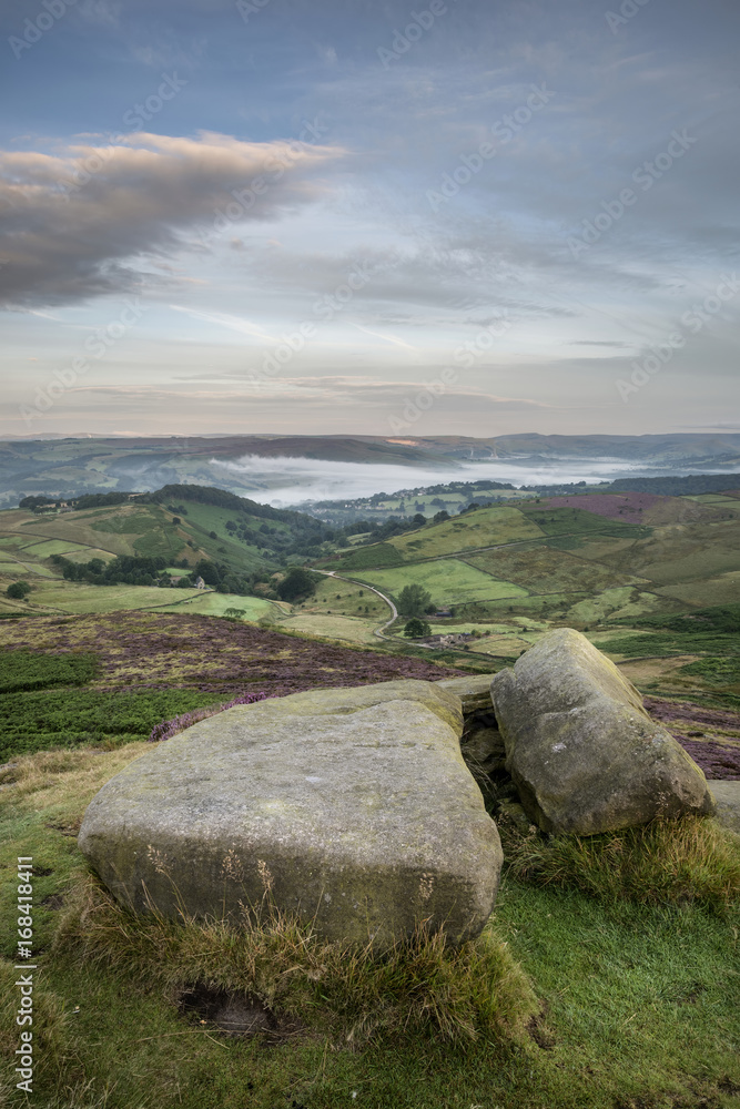 Stunning dawn sunrise landscape image from Higger Tor towards Hope Valley layered in fog in Summer in Peak District England