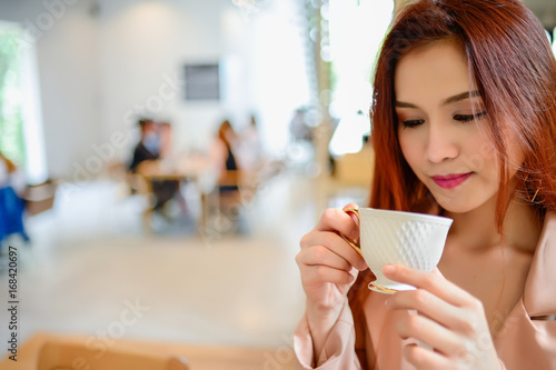 Portrait of beautiful woman and holding a cup of coffee in her hand in blur background coffee shop  she drink coffee in the morning