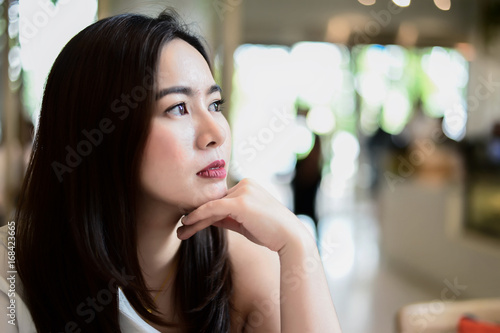 Portrait of beautiful asian woman sit on the chair in blur background restaurant. she is waiting for someone.