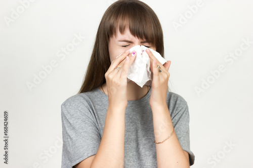 Portrait of a pretty woman having flu. Girl blowing nose. Black and white with red accent.