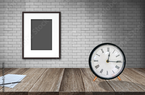 Blank photo frame on old brick wall and paper and vintage alarm clock