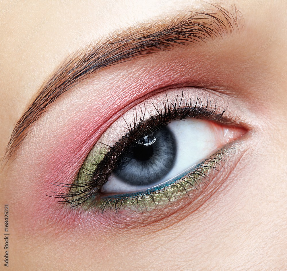 Fototapeta premium Closeup macro image of human woman eye with pink and green makeup