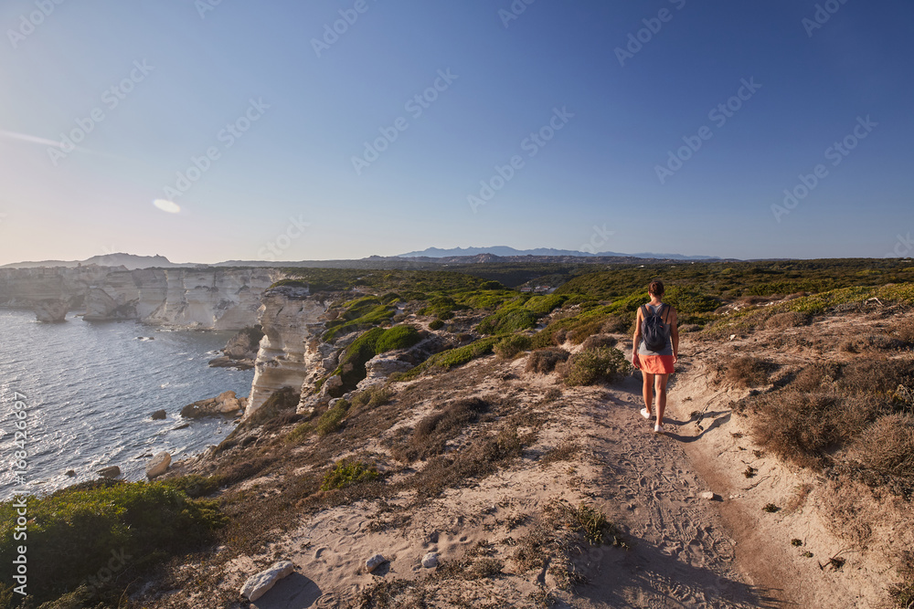 Fototapeta premium Ragazza di schiena cammina fra i sentieri di Bonifacio