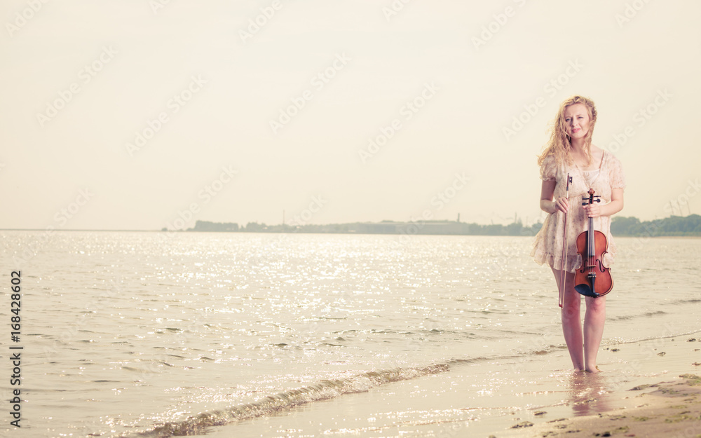 Woman on beach near sea holding violin